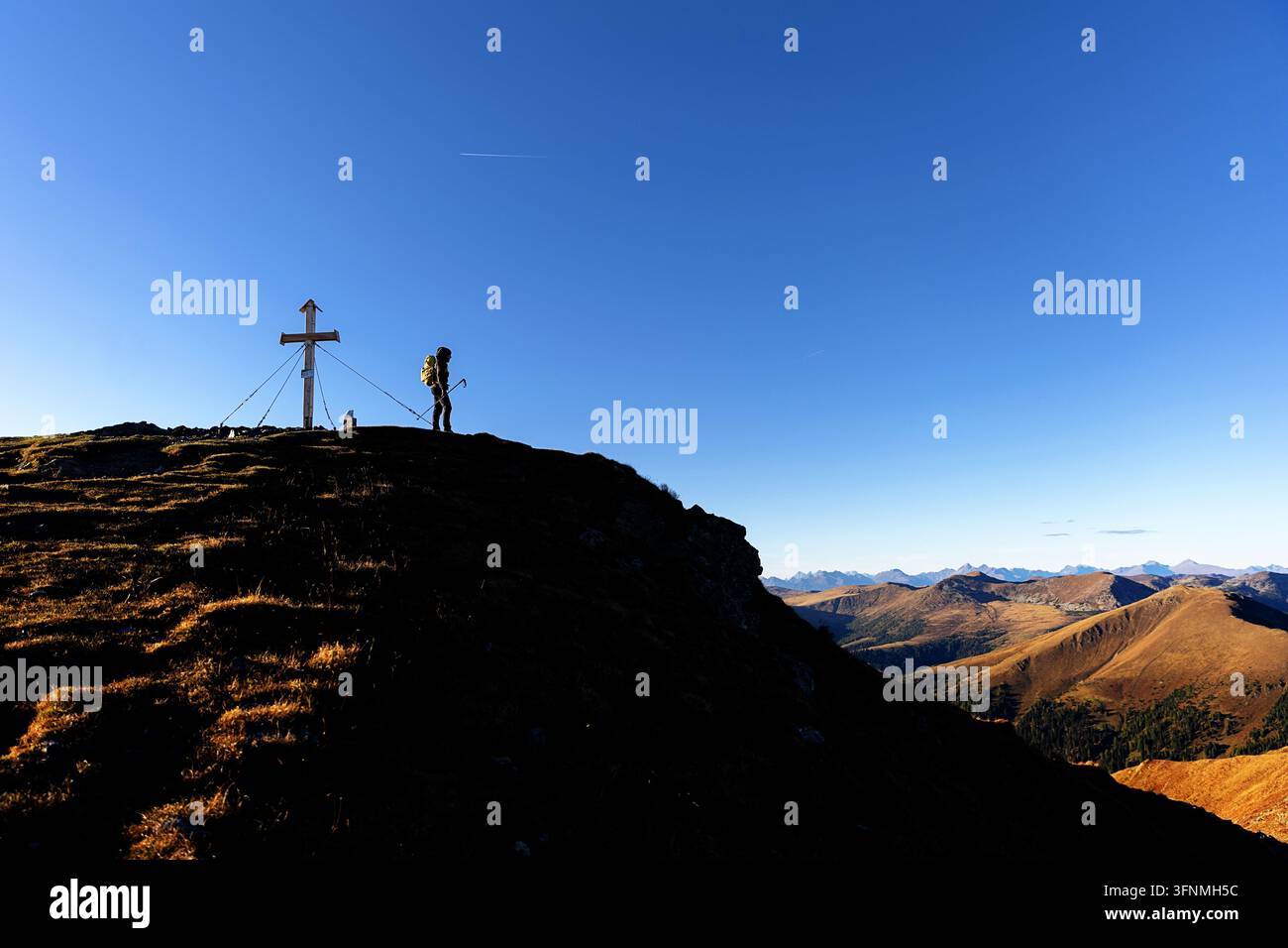 Un escursionista turistico con uno zaino che trekking su per i pendii dorati autunnali del monte Klomnock all'interno della riserva della biosfera scenografica di Nockalm, Austria Foto Stock