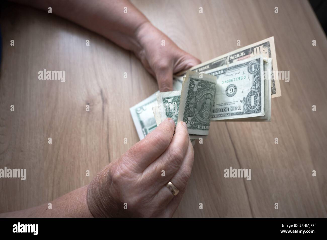 Un modesto budget familiare; dollari nelle mani di anziani. Foto Stock