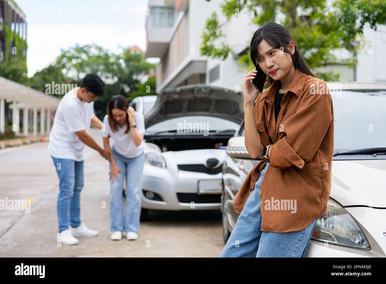 Le conducenti asiatiche chiamano l'assicurazione dopo un incidente stradale prima di scattare foto e inviarle all'assicurazione. Emergenza incidente stradale, mentre un'altra persona dieci Foto Stock
