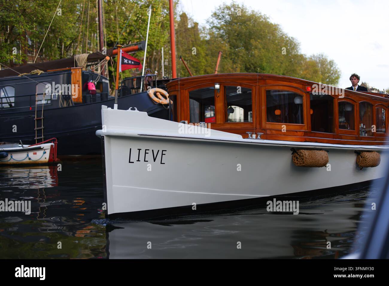 Amsterdam, Paesi Bassi – 1 ottobre 2026: Una nave passeggeri Lieve con una cabina in legno lucido naviga lungo un canale cittadino. Foto Stock