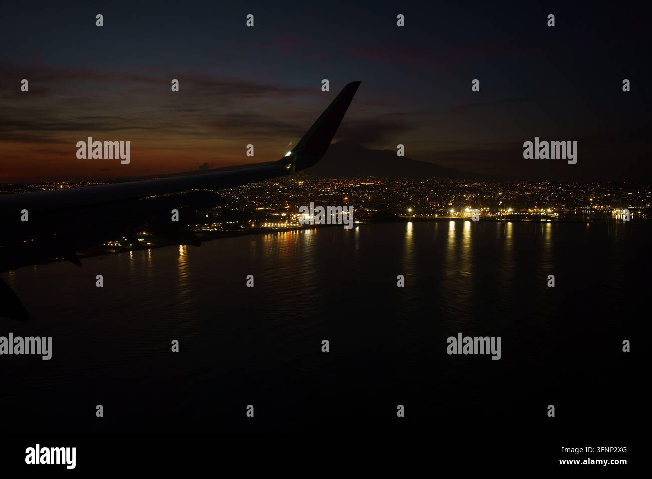 Vista aerea dalla finestra di un aereo di notte, paesaggio urbano di Catania, Italia, durante l'avvicinamento all'atterraggio, vista dell'Etna, prospettiva aerea delle luci urbane e della costa di notte, avventura di volo Foto Stock
