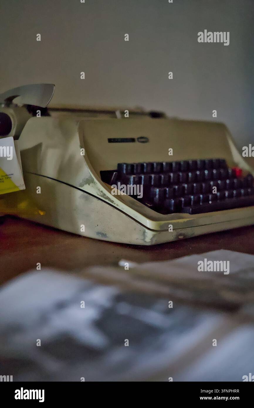 Un piano a fuoco selettivo di una macchina da scrivere meccanica vintage beige appoggiata su una scrivania di legno, che evoca temi di giornalismo nostalgico, scrittura classica e Foto Stock