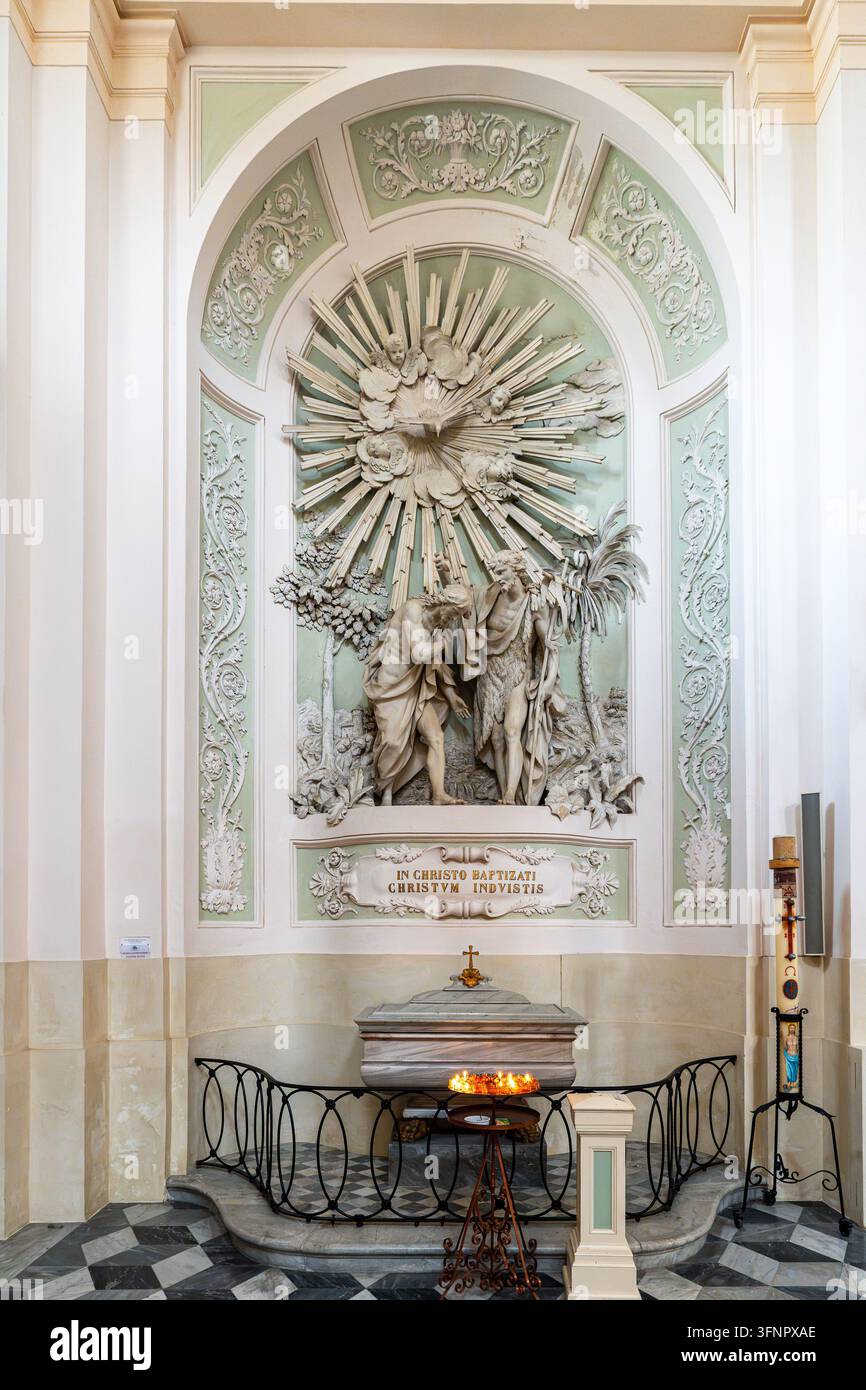 Un primo piano della fonte battesimale nella Cattedrale di Urbino. Sopra il bacino di marmo si distingue un grande rilievo in stucco raffigurante il Battesimo di Cristo Foto Stock