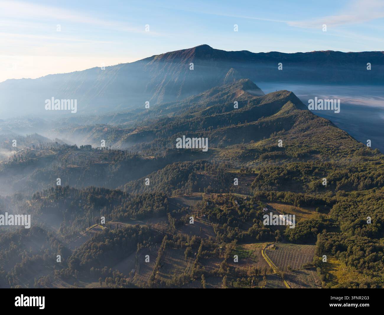 La cresta montuosa nebbiosa si innalza sopra le valli verdeggianti a Cemoro Lawang Foto Stock