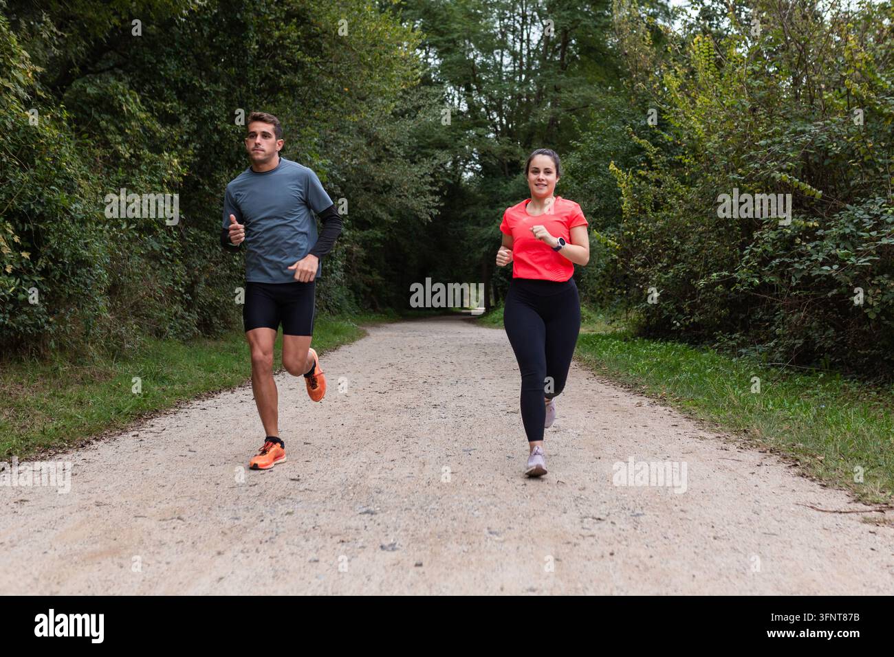Viaggio verso la forma fisica: Due individui a metà passo su un percorso di jogging panoramico Foto Stock