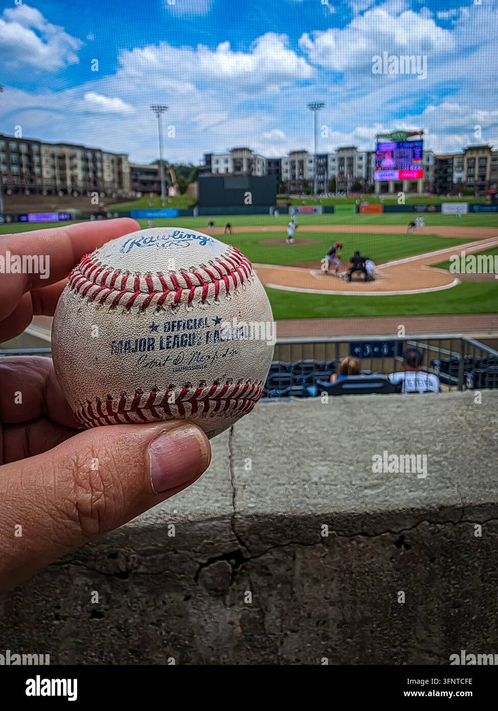 Lawrenceville, Georgia, USA, 11 giugno 2025: Ritratto attraverso una rete di una palla da baseball Rawlings consumata, lettere ufficiali della Major League Baseball visibili Foto Stock