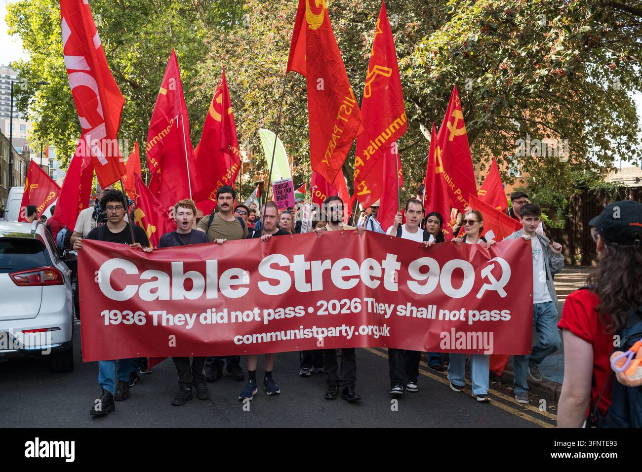 Marcia del 90° anniversario a Cable Street a Londra, con bandiere e striscioni del Partito Comunista che commemorano la battaglia di Cable Street del 1936 Foto Stock