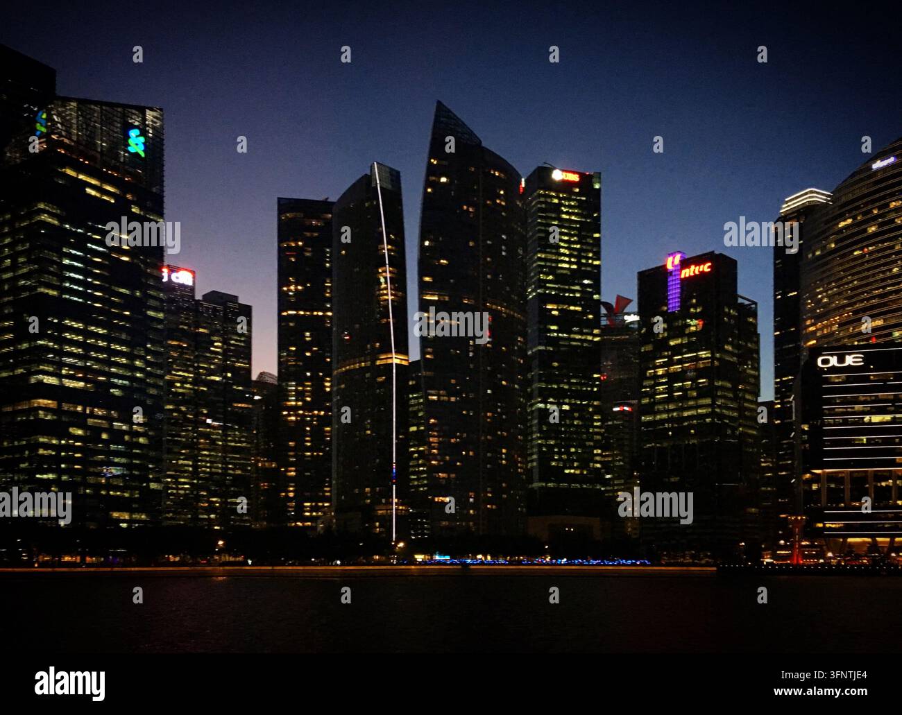 Lo skyline di Singapore al crepuscolo, febbraio 2019. Grattacieli illuminati si ergono sulla città, con progetti architettonici distintivi. Gli edifici sono Foto Stock