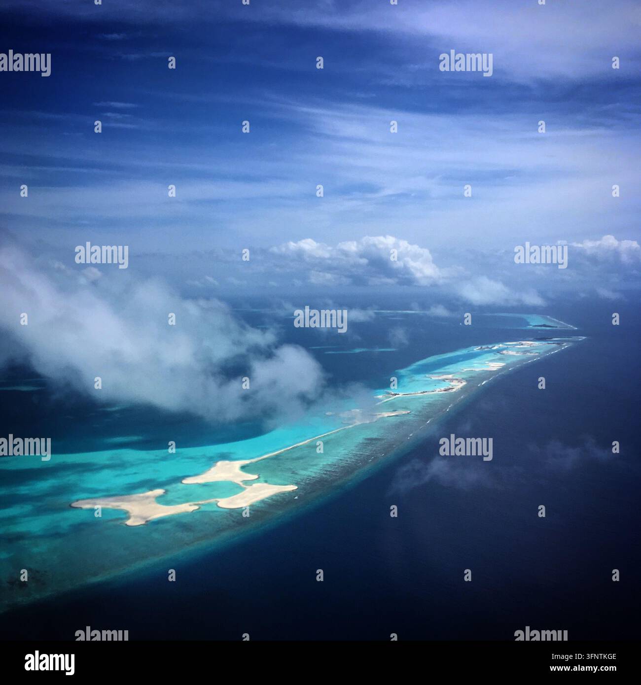 Vista aerea di una serie di piccole isole e atolli alle Maldive, circondati da acque limpide e turchesi. Le isole appaiono come macchie di sabbia nel mezzo del t Foto Stock