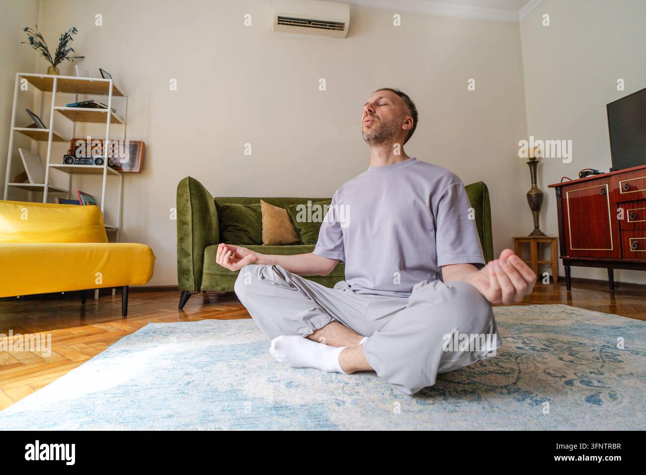 Uomo che pratica meditazione e consapevolezza a casa con respirazione calma per il rilassamento, l'alleviamento dello stress, il benessere, la pace interiore e l'attenzione concentrata durante la cura personale silenziosa. Foto Stock