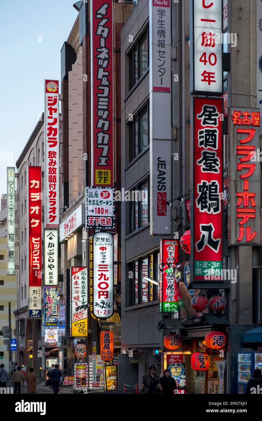 Insegne al neon di attività commerciali giapponesi illuminano la sera nel quartiere dell'intrattenimento vicino alla stazione centrale di Nagoya (名古屋), Aichi, Giappone. Foto Stock