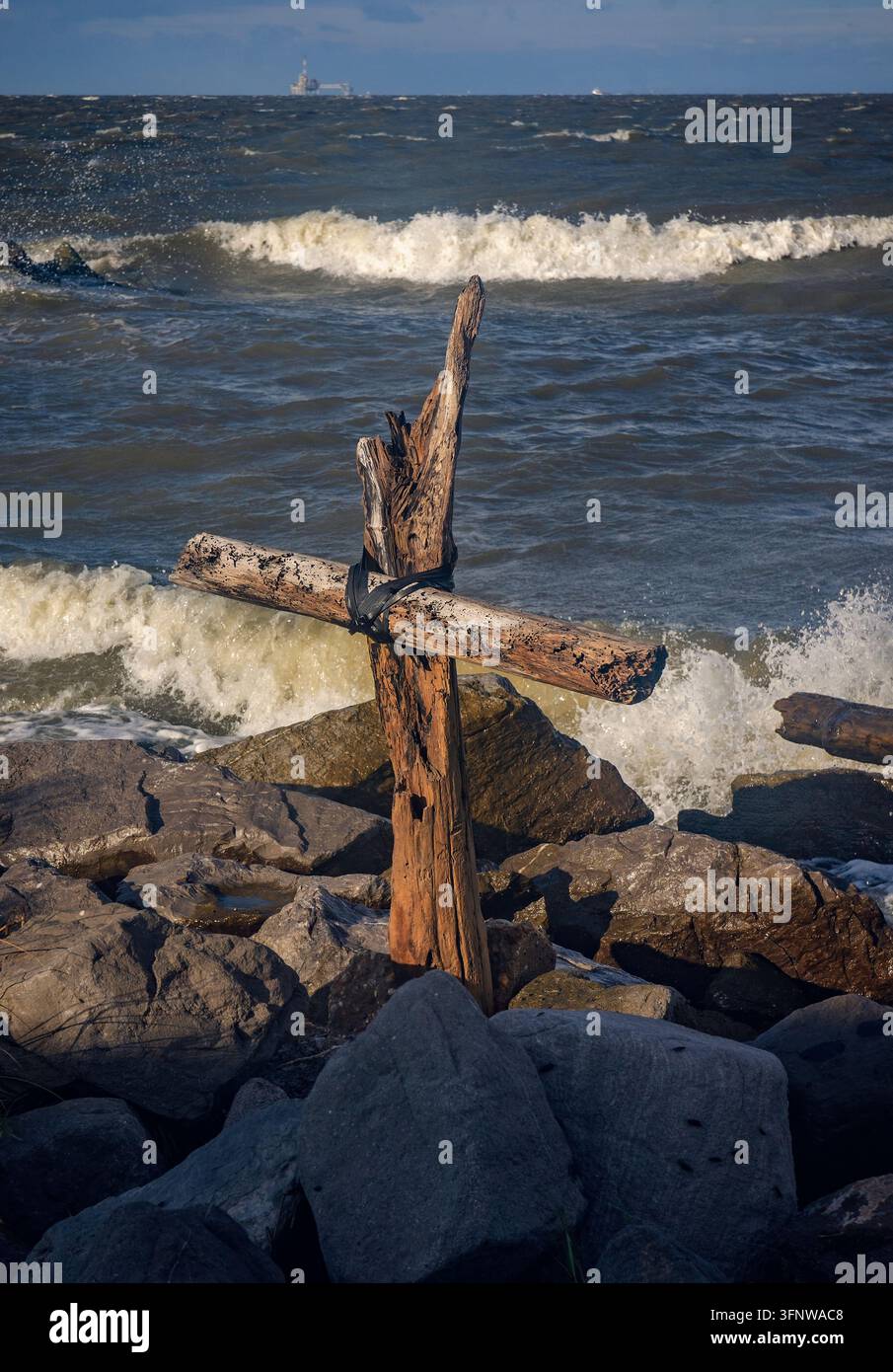 Una croce di legno alla deriva si erge tra le onde infrante mentre l'uragano Helene si avvicina alla costa del Golfo, il 26 settembre 2024, a Dauphin Island, Alabama. Foto Stock