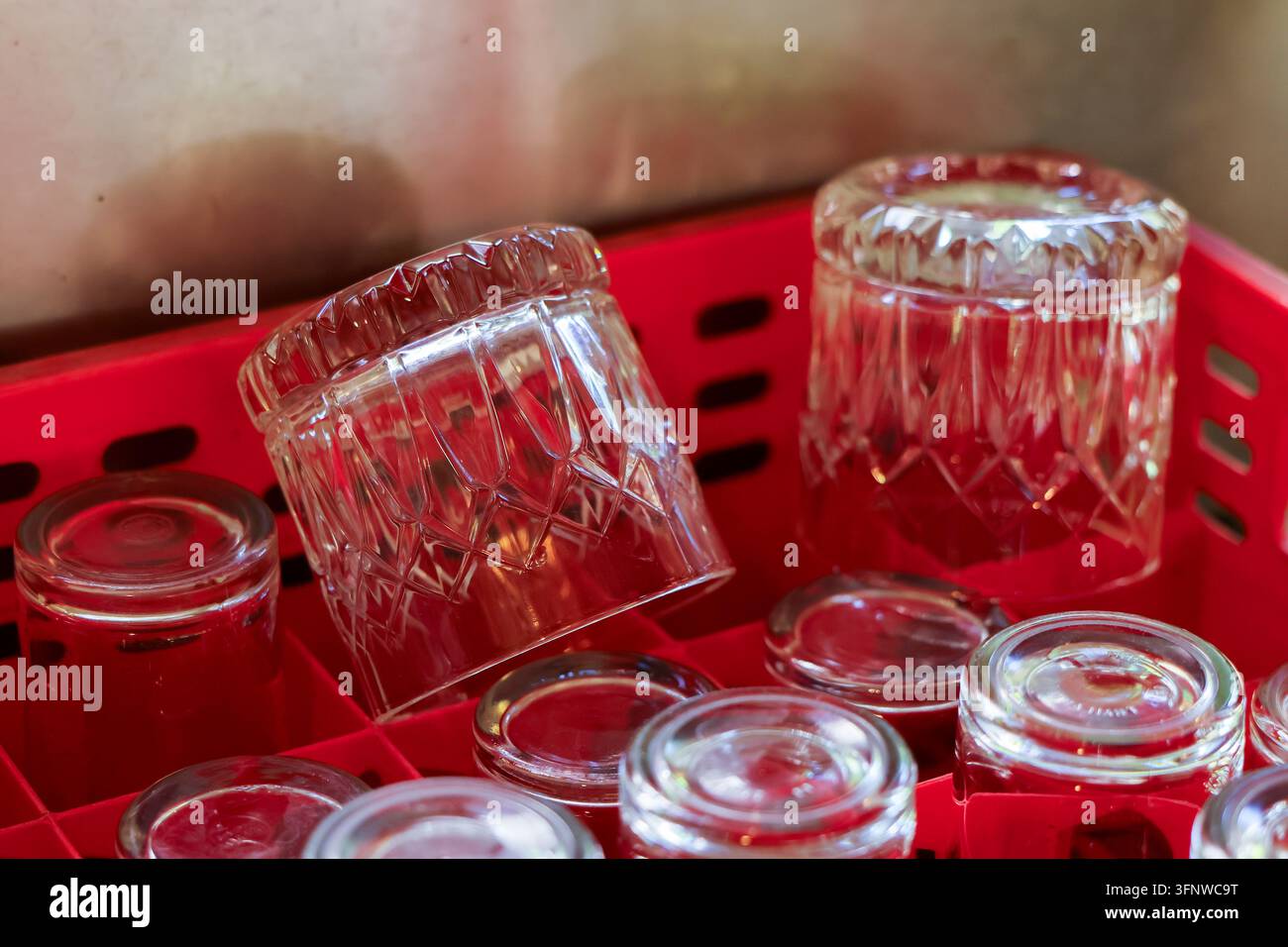 Un bicchiere di vetro trasparente e un barattolo disposti in un cestino di plastica rosso Foto Stock