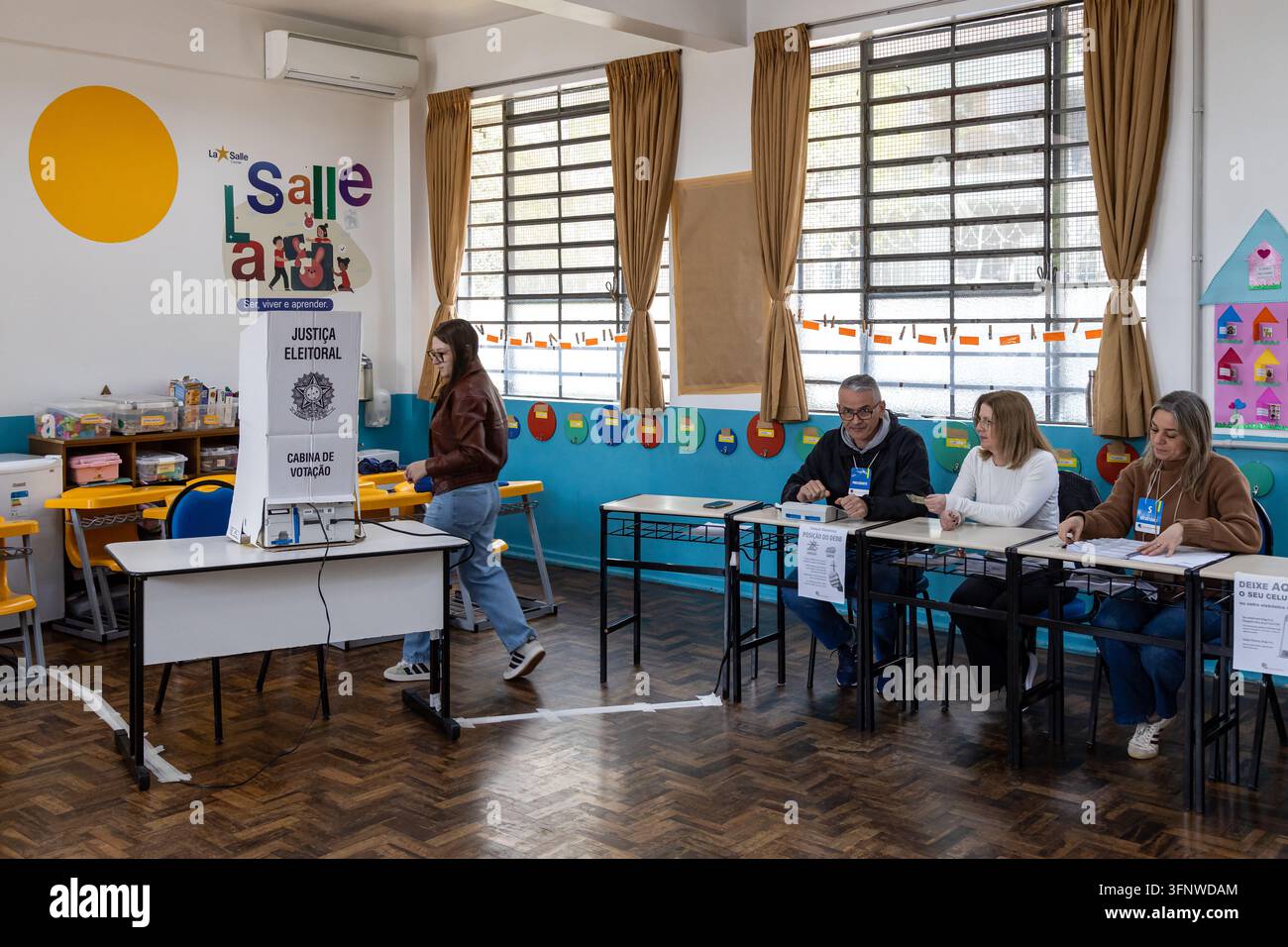 Caxias do Sul, RS, Brasile – 4 ott. 2026: Funzionari di seggio ed elettore in un seggio elettorale durante le elezioni brasiliane Foto Stock
