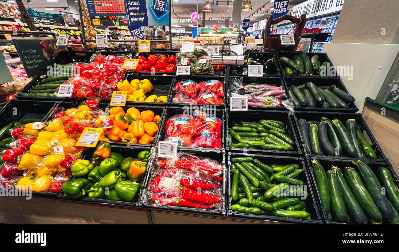 Germania, Europa. Un'ampia sezione di ortaggi di un moderno supermercato con una vasta selezione di peperoni freschi, cetrioli, zucchine, melanzane e altre verdure di stagione. Prodotti confezionati e sfusi, cartellini dei prezzi ben visibili e cartelli pubblicitari documentano il commercio al dettaglio alimentare tedesco e l'offerta variegata di prodotti freschi. L'immagine è adatta per reportage editoriali su prezzi dei generi alimentari, inflazione, nutrizione, commercio al dettaglio, consumo, prodotti regionali e approvvigionamento di prodotti freschi. *** Germania, Europa Un ampio reparto ortofrutticolo Foto Stock