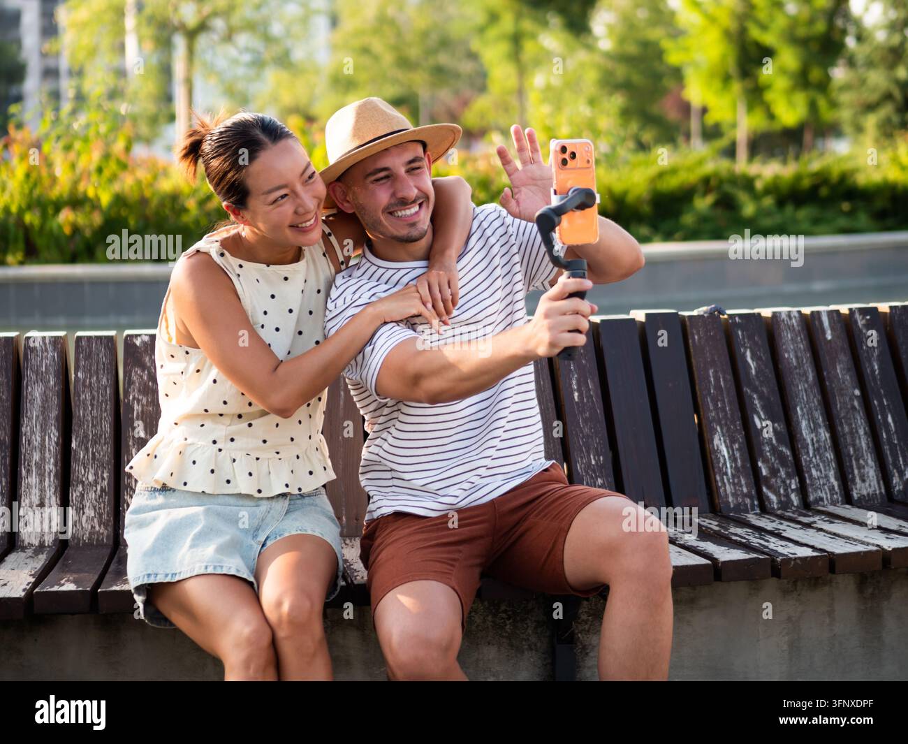 Coppia felice che realizza un vlog mobile insieme ridendo e godendosi un pomeriggio soleggiato nel parco. Foto Stock