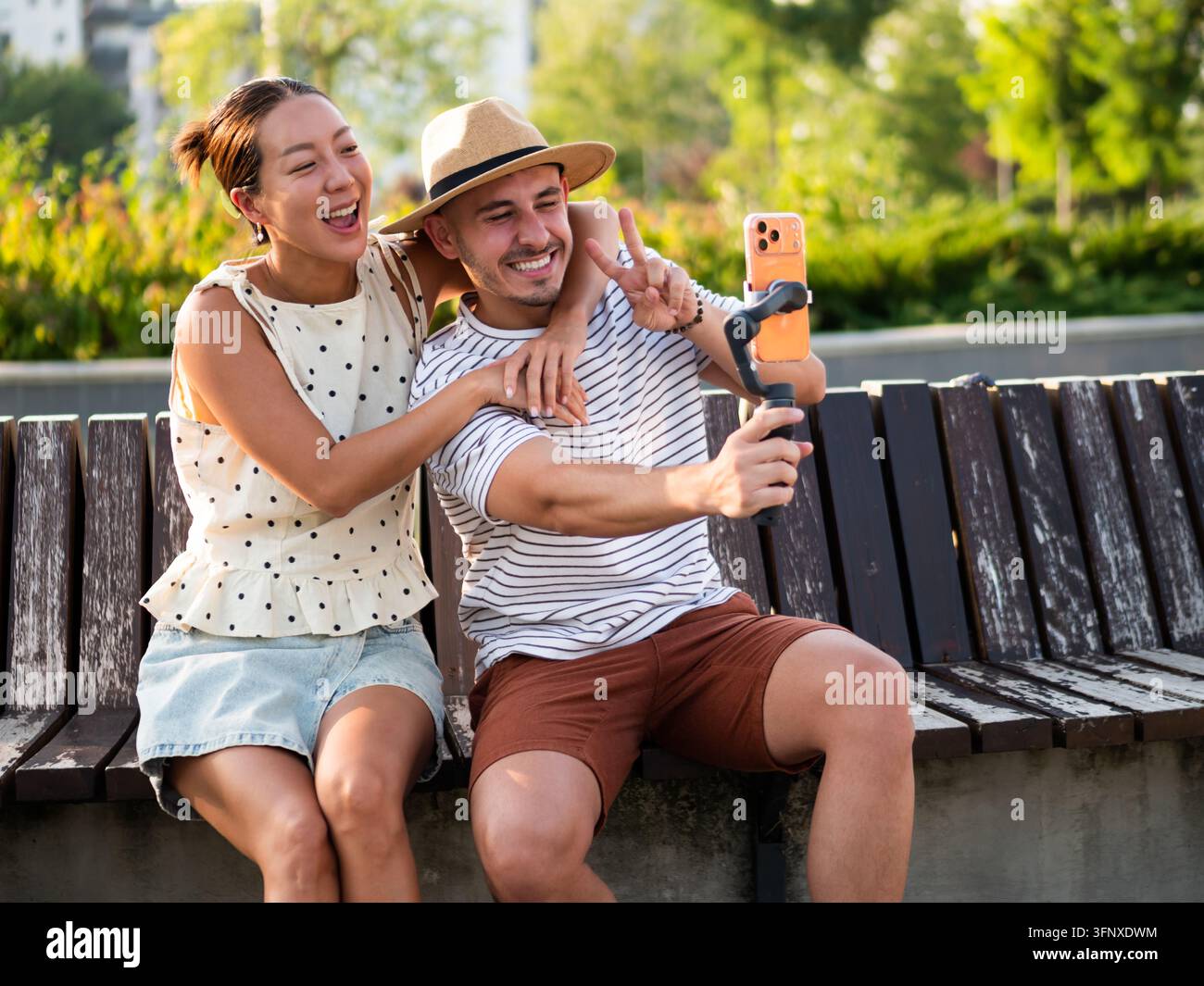 Coppia gioiosa che si abbraccia e fa un segno di pace mentre registra un video insieme. Foto Stock