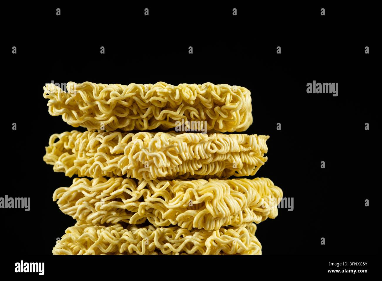 Pila di blocchi di noodle istantanei secchi Ramen isolati su sfondo nero Foto Stock