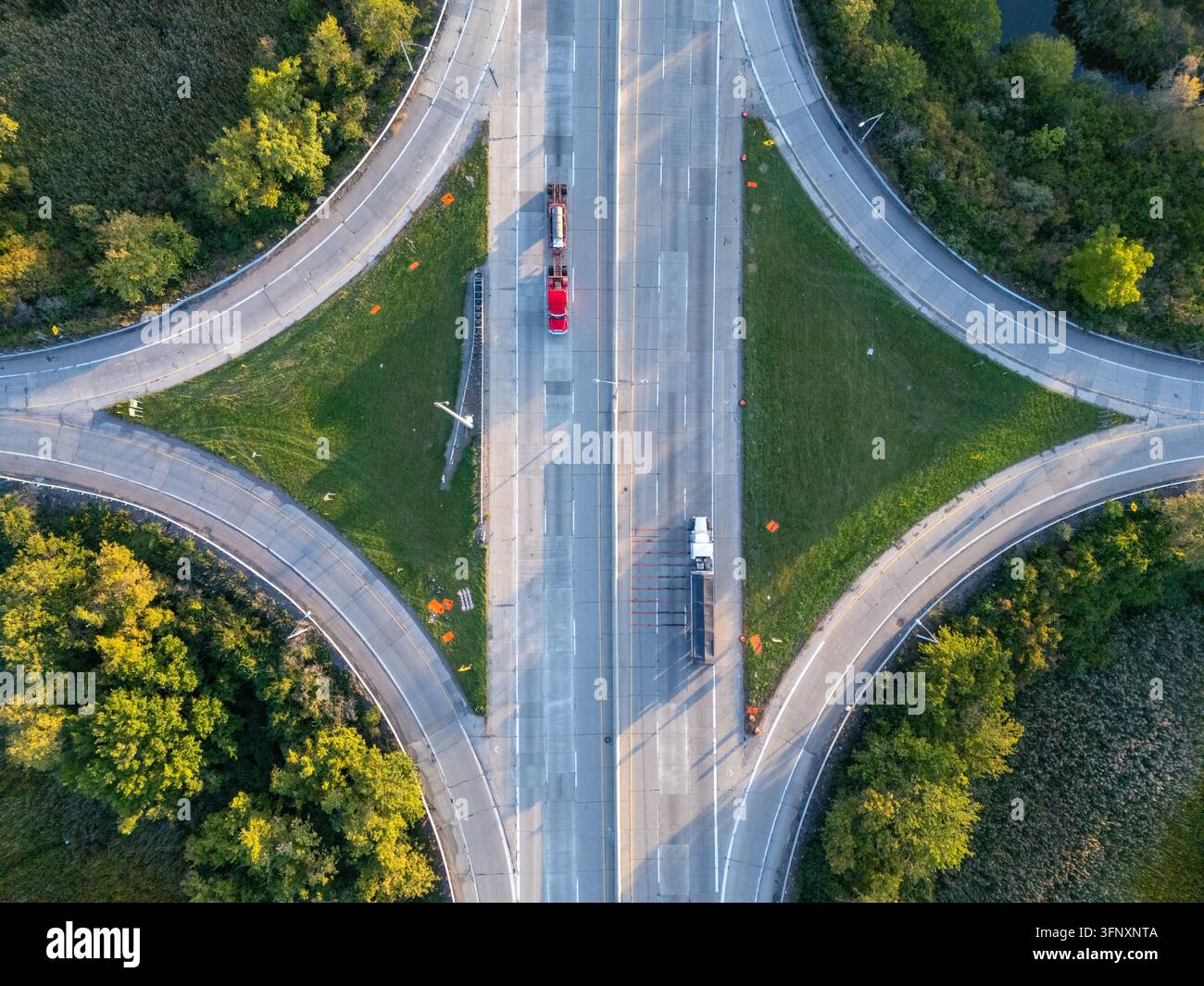 Vista aerea dello svincolo dell'autostrada I-75 con camion che viaggiano sull'autostrada circondata da alberi verdi e mediane erbose a Monroe, Michigan, Stati Uniti Foto Stock