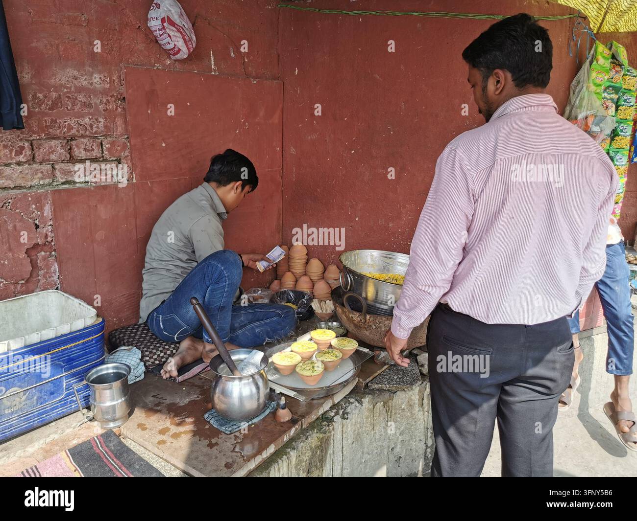VARANASI, INDIA - 22 GENNAIO 2026: Un venditore di strada serve cibo in tradizionali tazze di argilla a una bancarella del mercato a Varanasi. Foto Stock