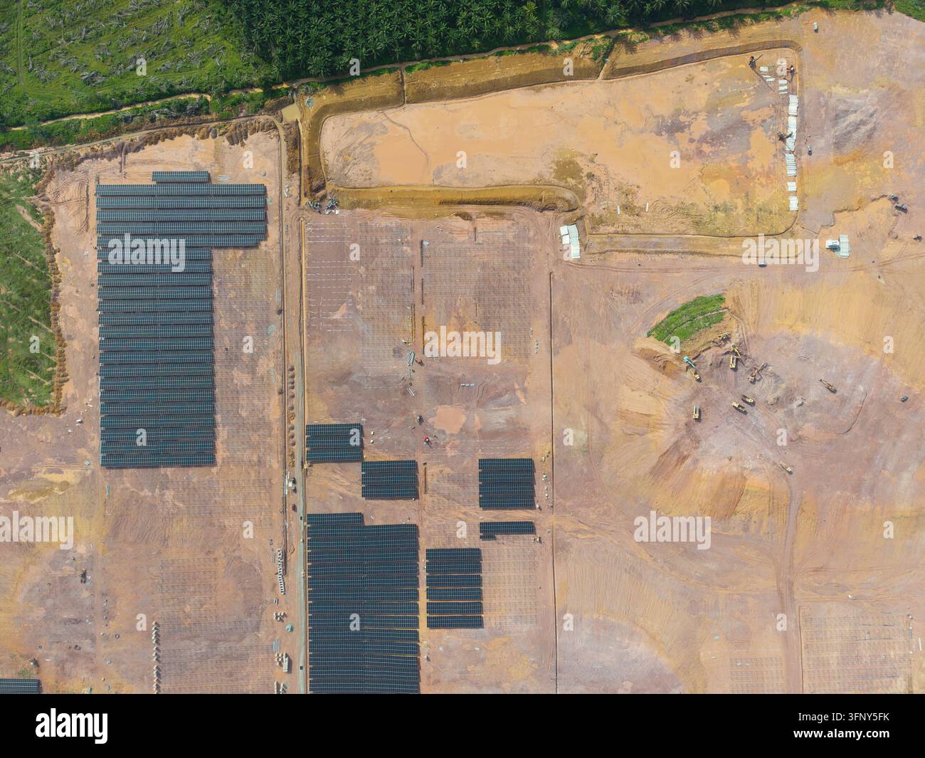 Vista aerea di un'installazione di pannelli solari in un cantiere edile con scavi e macchine pesanti a Kulai, Johor, Malesia. Foto Stock