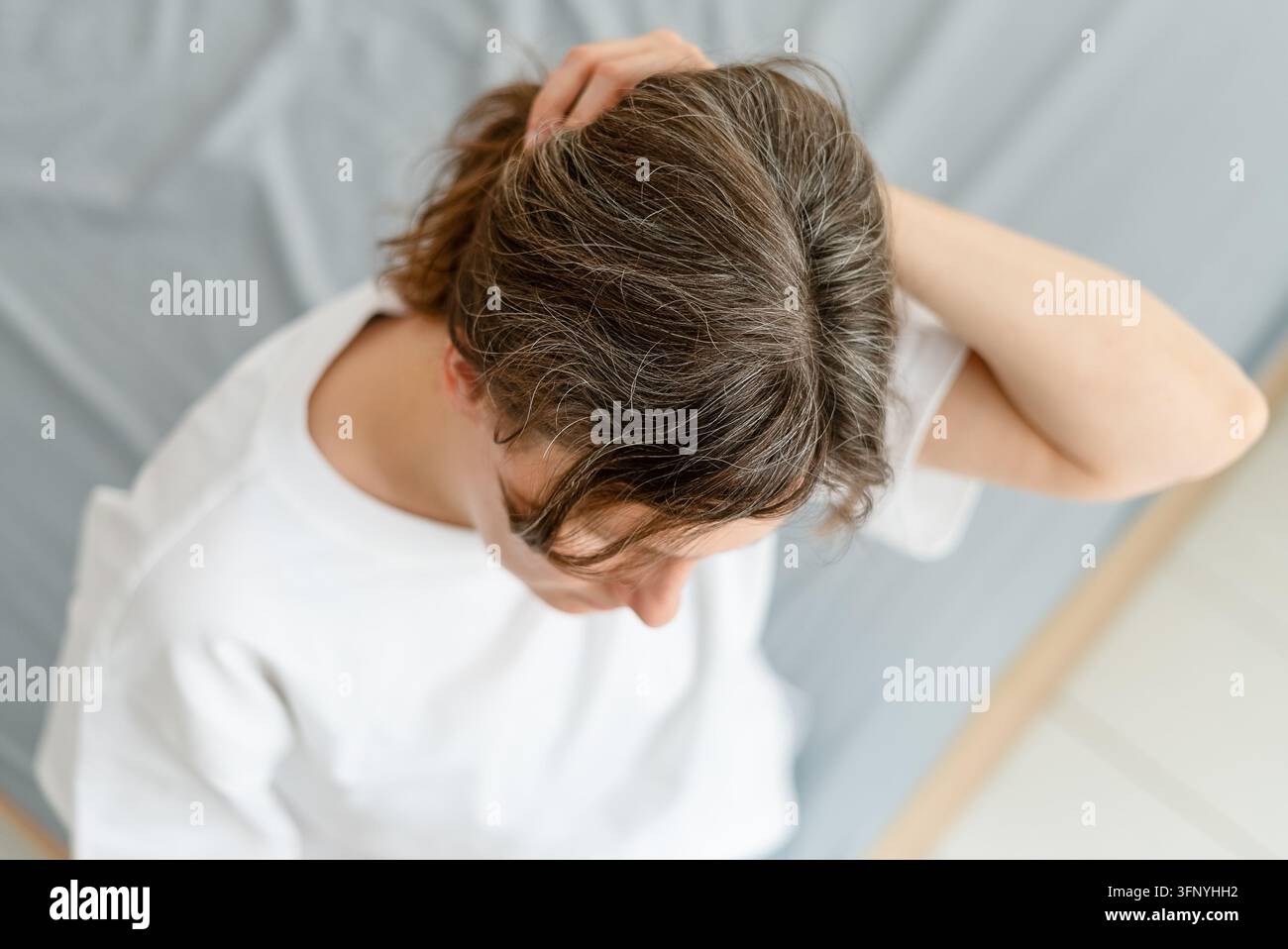Una neomamma nota capelli grigi che compaiono dopo aver dato alla luce il suo bambino. La donna vede come la gravidanza e il parto hanno influenzato il colore dei suoi capelli. Annuncio maturo Foto Stock