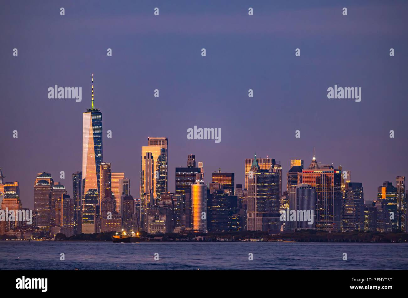 Vista panoramica dei grattacieli del distretto finanziario di Lower Manhattan con il One World Trade Center al crepuscolo sopra il fiume Foto Stock