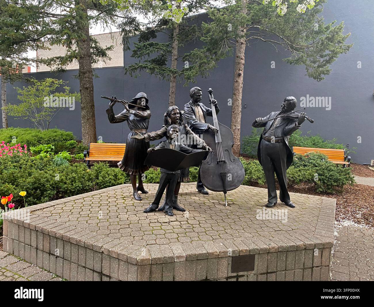 La Gioia della Musica sculture in bronzo di tre adulti che suonano strumenti e due bambini che cantano realizzati da George Lundeen, su una piattaforma di mattoni, esposti - Immagine stock catturata con smartphone