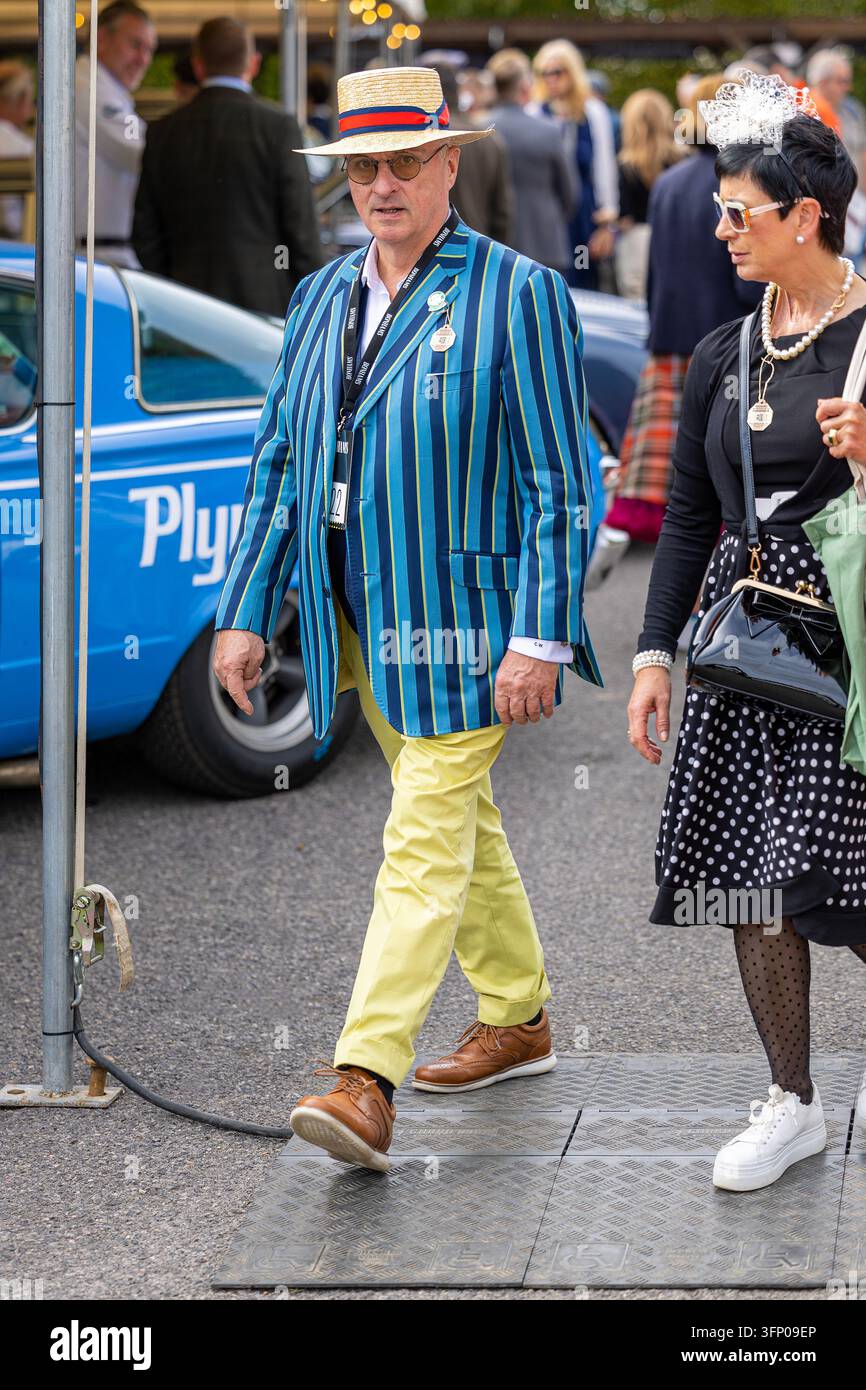 Uomo con cappello a cilindro e giacca a righe, spettatori in costume d’epoca che camminano durante l’evento Goodwood Revival al Goodwood Motor Circuit, West Sussex. Foto Stock