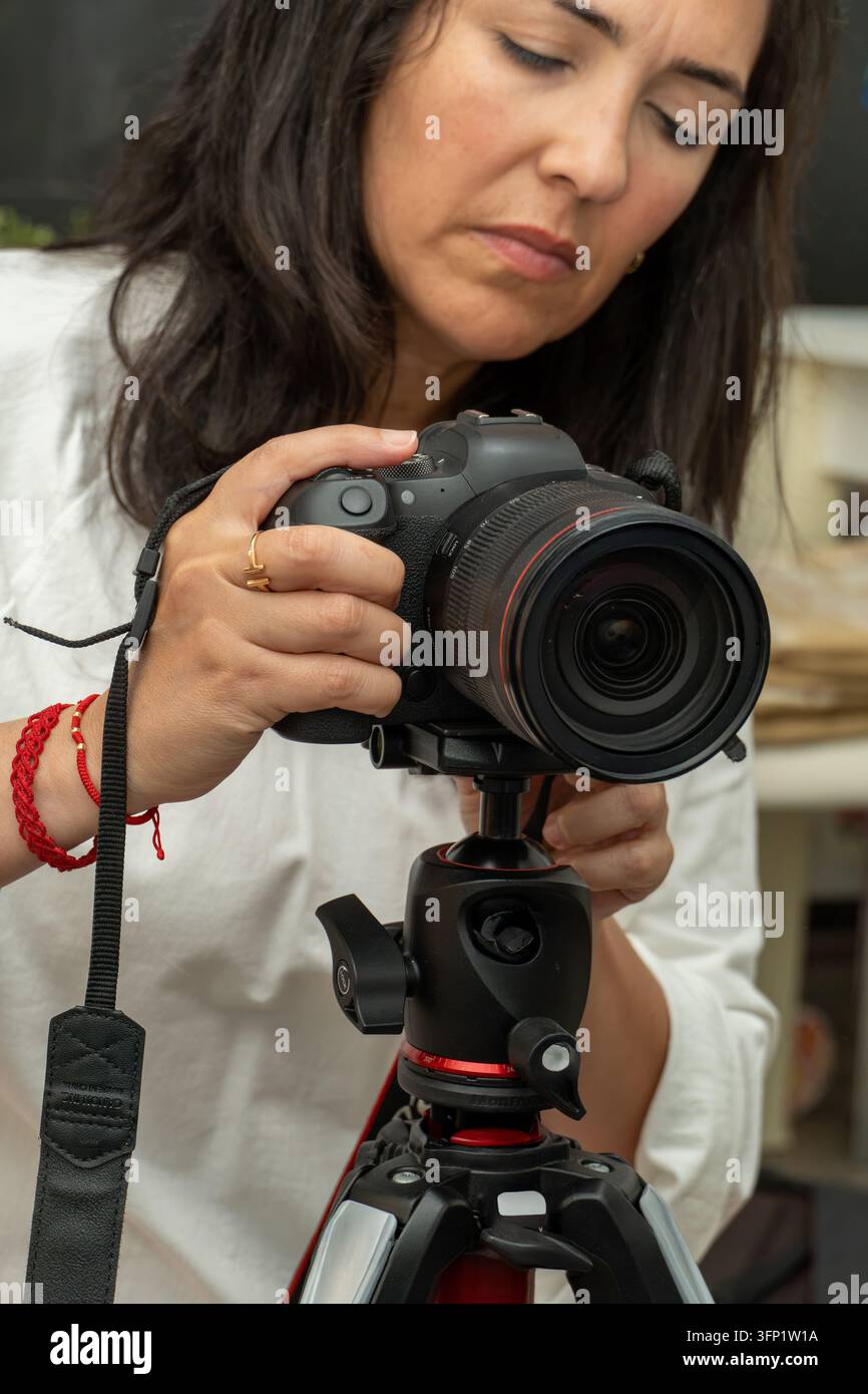 Donna che regola la fotocamera su treppiede per una sessione fotografica Foto Stock