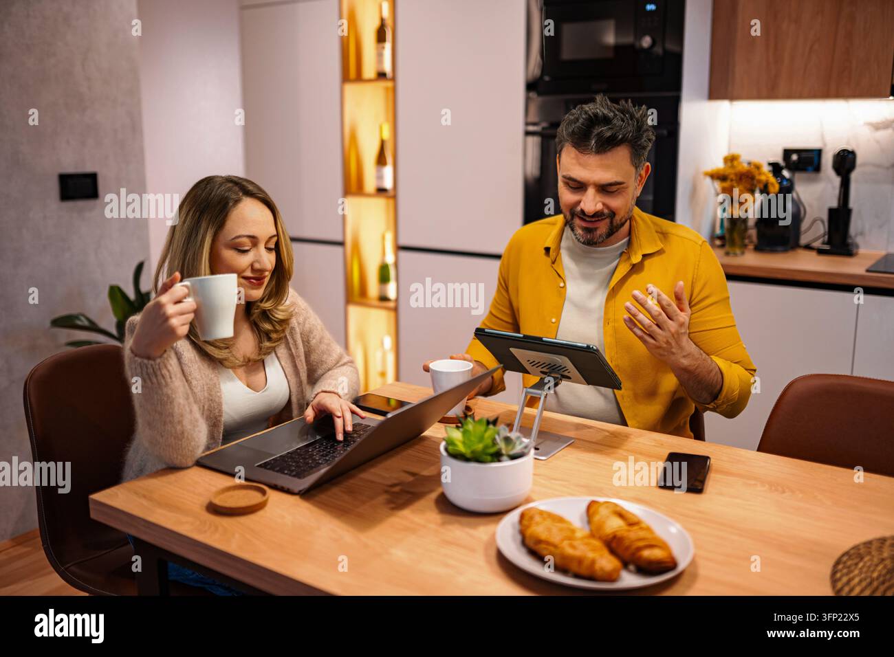 Coppia che lavora da casa in una cucina moderna Foto Stock
