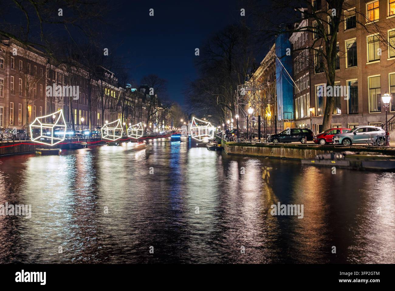 Vista di installazioni di arte luminosa illuminate che galleggiano su un canale di notte, con case storiche dei canali e riflessi nell'acqua ad Amsterdam, Nord Foto Stock