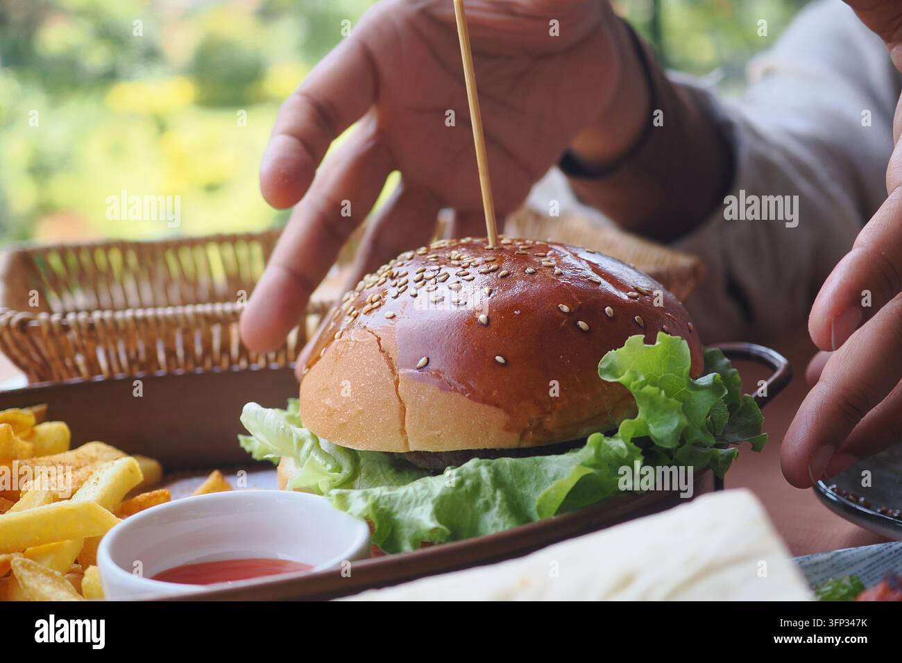 Un uomo si prepara a mangiare un hamburger con patatine fritte a un tavolo del ristorante Foto Stock