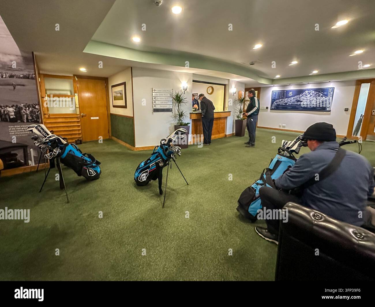 Golfisti e il loro equipaggiamento nell'area di ricevimento del clubhouse di St Andrews Links, con borse da golf, sedute e esposizioni interne. Foto Stock