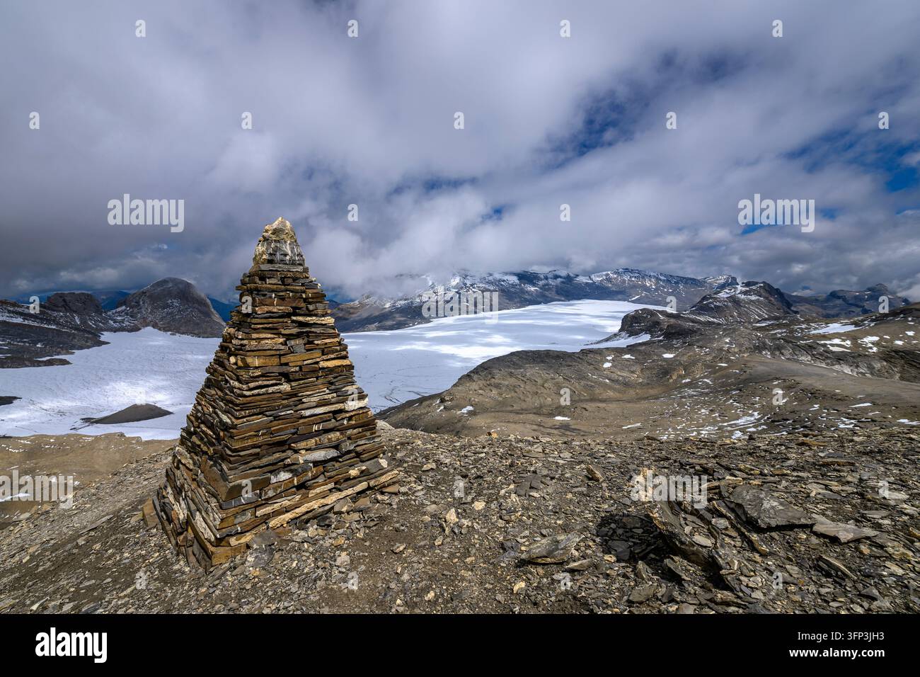 Un cumulo piramidale di pietra si erge su una cima rocciosa che si affaccia sul vasto ghiacciaio della Plaine Morte nel Vallese, Svizzera Foto Stock