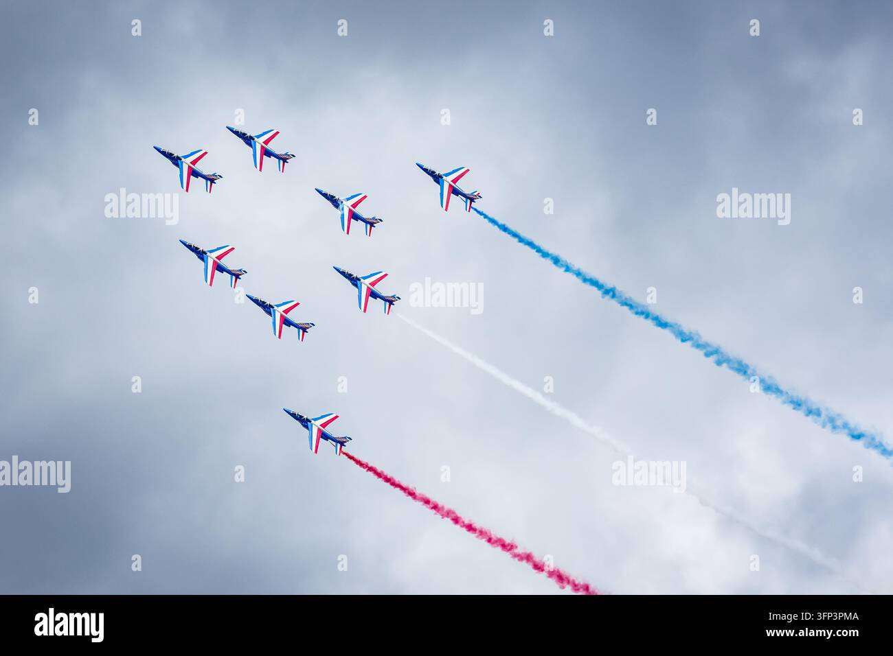 Gli otto Alpha Jet dell'unità acrobatica Patrouille de France volano in formazione Alpha con fumo blu, bianco e rosso durante una dimostrazione aerea. Foto Stock