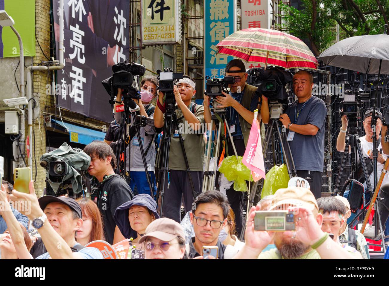 Taipei, Taiwan - 03 ott. 2026: Operatori di telecamere della stampa su treppiedi filmano un evento di campagna del Partito Progressista Democratico mentre i sostenitori alzano i telefoni. Foto Stock