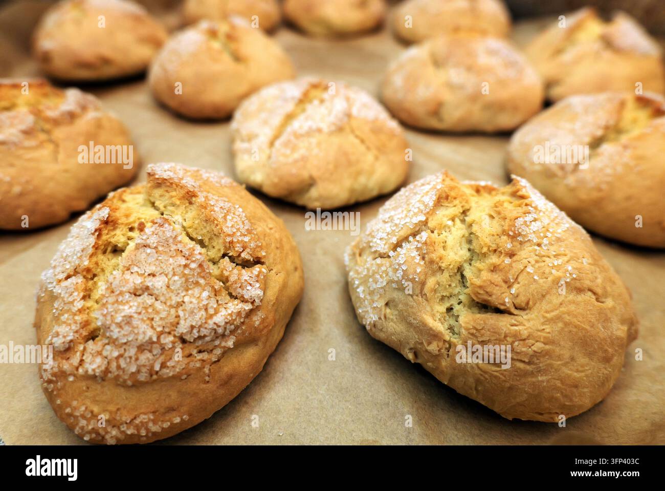 Biscotti che cuociono su una teglia con una texture dorata rustica e una leggera spolverata di zucchero, caldi appena sfornati, evidenziando dolcetti freschi, fatti in casa e cr Foto Stock