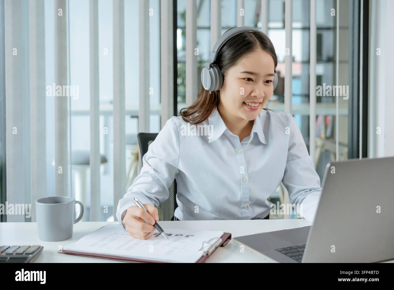 Help desk dell'operatore del servizio di assistenza clienti sorridente. Giovane operatore donna asiatica agente con cuffie e auricolari in funzione hotline di supporto in un call center Foto Stock