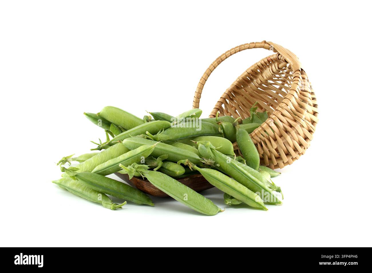 Una rigogliosa raccolta di piselli verdi vibranti cade da un cesto di vimini capovolto, mostrando la loro freschezza e consistenza naturali Foto Stock