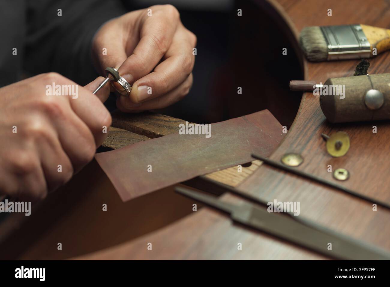 Tavolo da lavoro per la creazione di gioielli artigianali con strumenti professionali. Maestro di gioielleria lucidato manualmente anello d'oro con diamanti. Anello di matrimonio con diamanti su Foto Stock