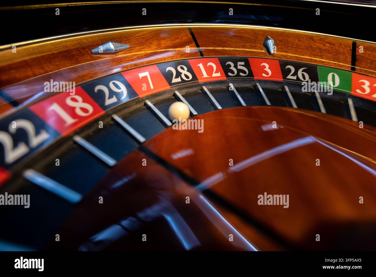 Una vera ruota della roulette vintage mostra una palla d'avorio accanto alla casella rossa numero 7. L'attrezzatura da casinò antica autentica mostra un bordo in legno lucidato. Foto Stock