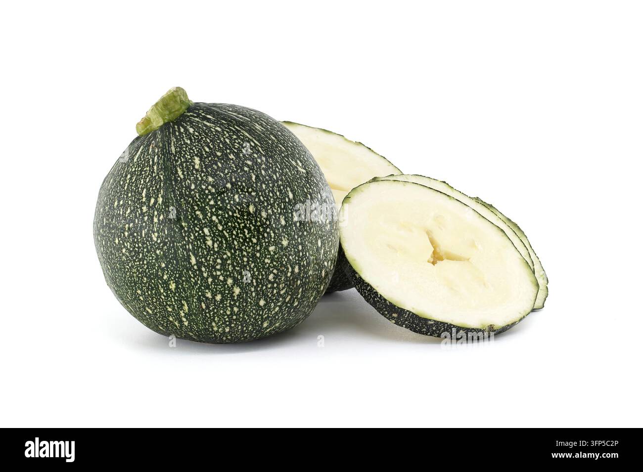 Una zucchina intera e rotonda con una buccia verde scuro screziata si trova accanto a due pezzi affettati che rivelano la sua polpa pallida e i semi Foto Stock