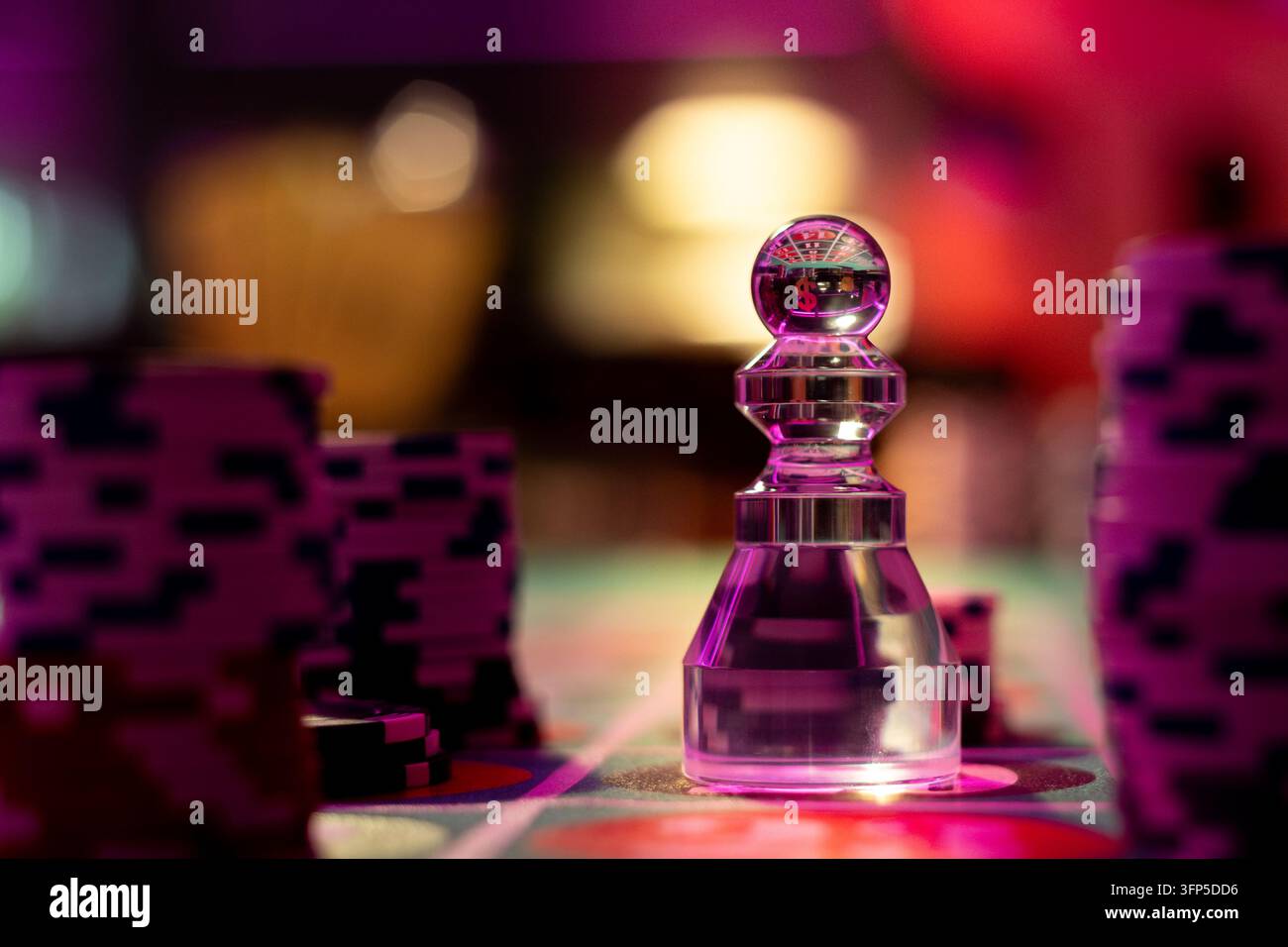 Dolly trasparente per il roulette in vetro si erge su un tappeto verde da gioco. Alte pile di gettoni di scommessa viola e neri fiancheggiano il segnaposto vincente. Foto Stock
