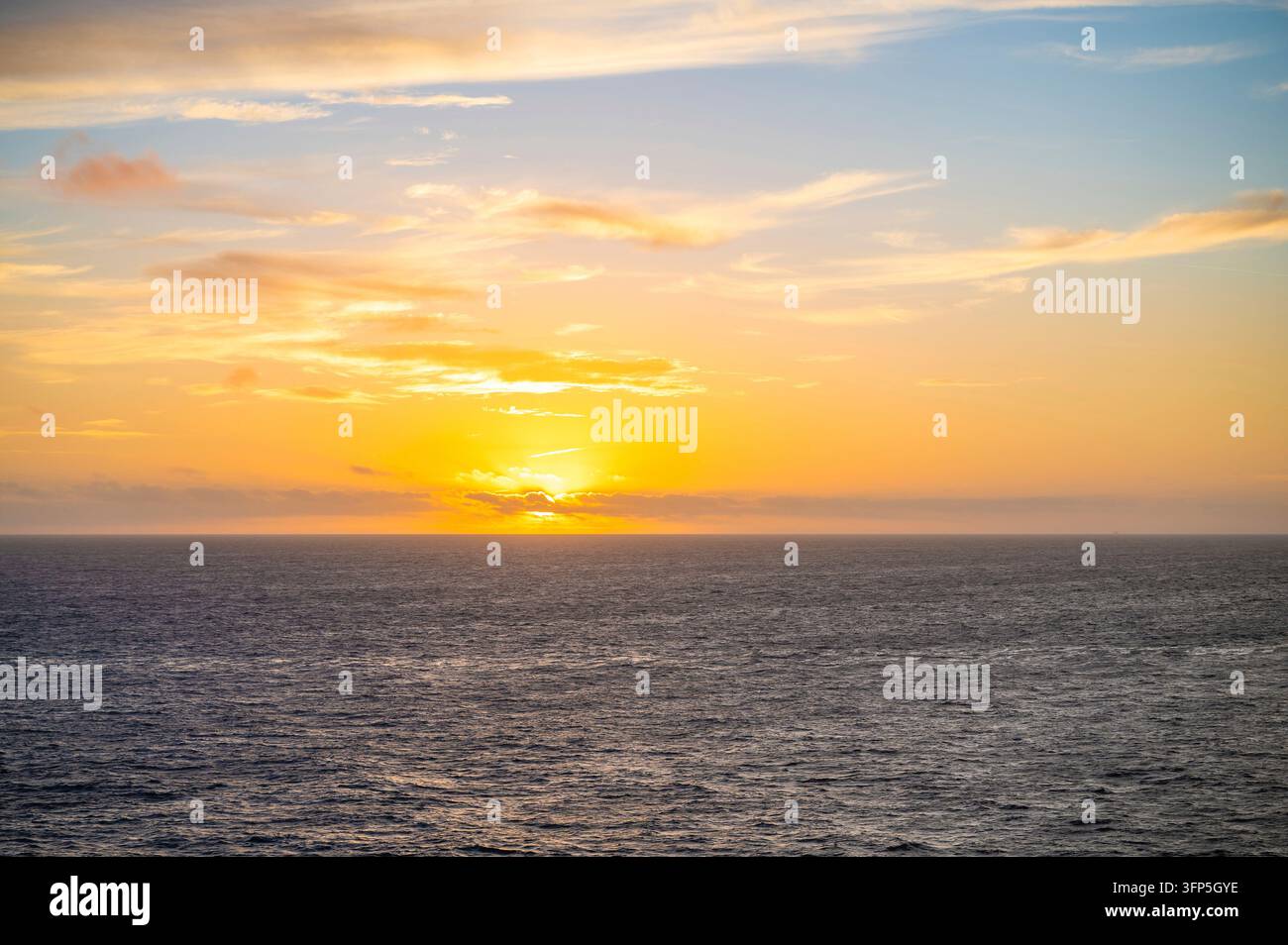 Un tranquillo tramonto sull'oceano, che proietta una calda luce dorata sull'orizzonte Foto Stock