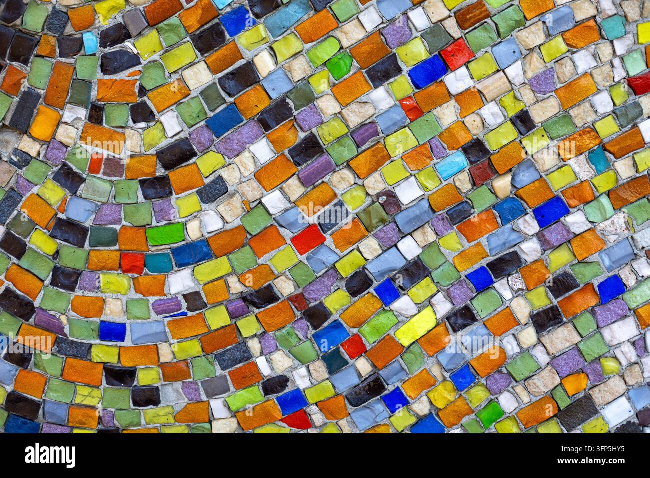 Motivo mosaico astratto colorato realizzato con piccole piastrelle di vetro irregolari, superficie decorativa vibrante con linee curve e texture geometrica multicolore. Foto Stock