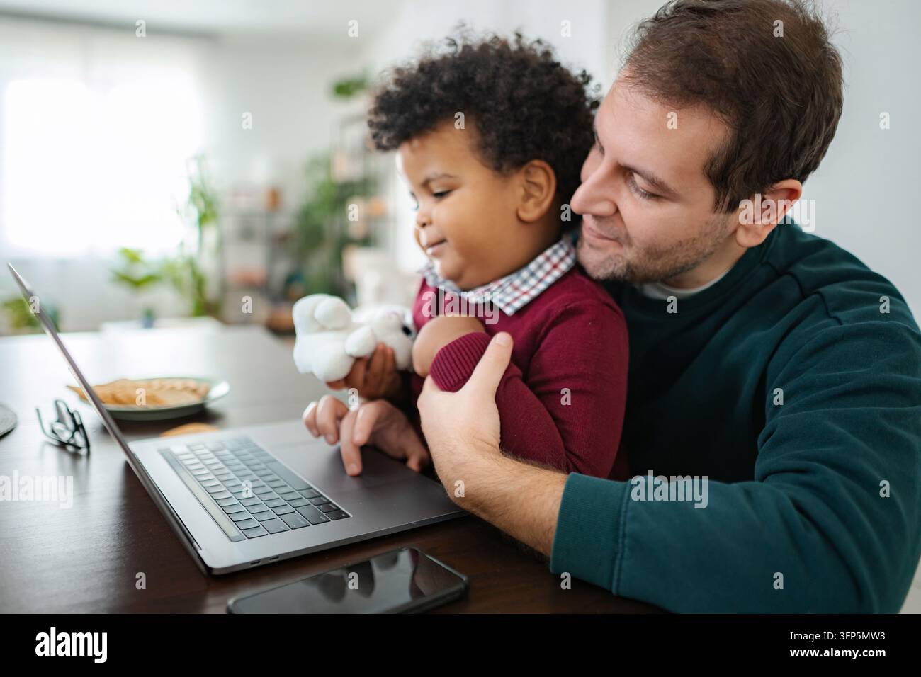 Padre e figlio che usano il laptop insieme a casa Foto Stock