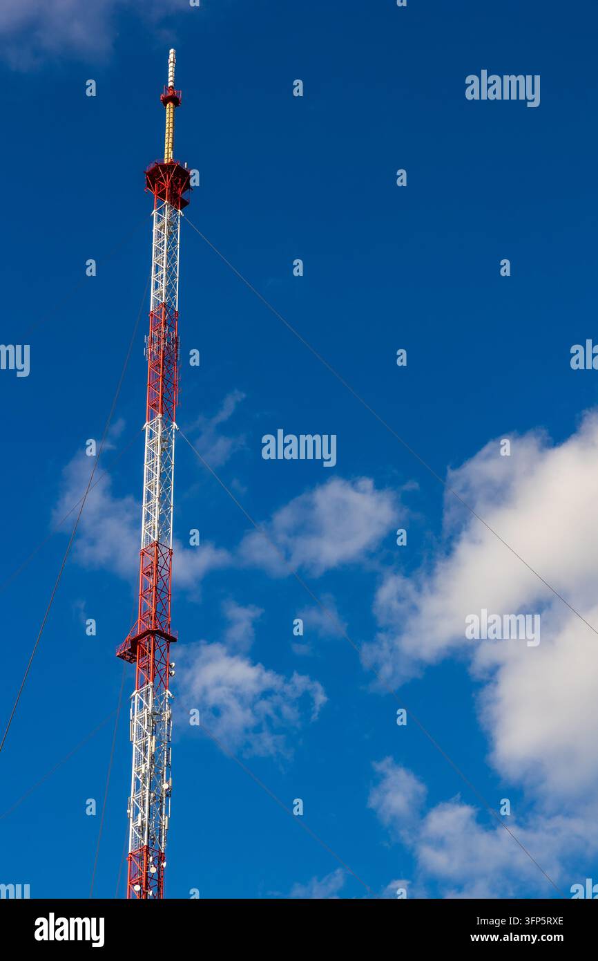 Torre di telecomunicazione rossa e bianca contro un cielo blu, infrastruttura di rete senza fili e trasmissione del segnale. Foto Stock