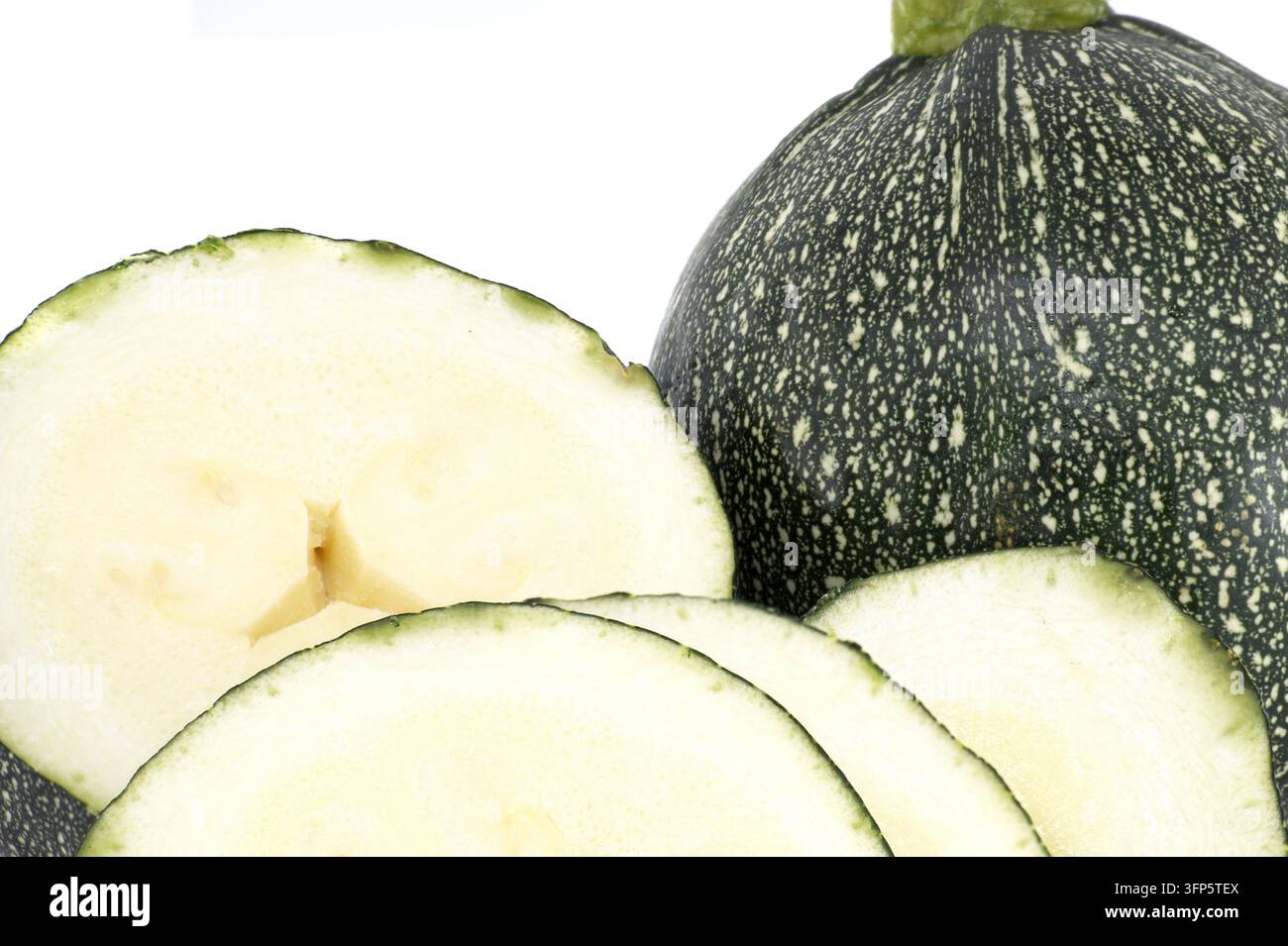 Zucca rotonda di zucchine con pelle macchiata verde scuro e interno chiaro, tagliata a fette per mostrare consistenza e semi. Verdure fresche estive ideali per cucinare, eh Foto Stock