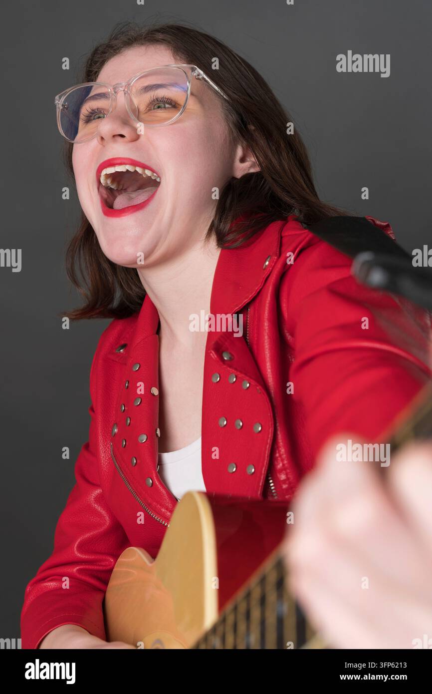 Giovane chitarrista felice in stato di pura gioia suonando la chitarra classica con passione, la bocca aperta, la voce risuona con potenti emozioni Foto Stock